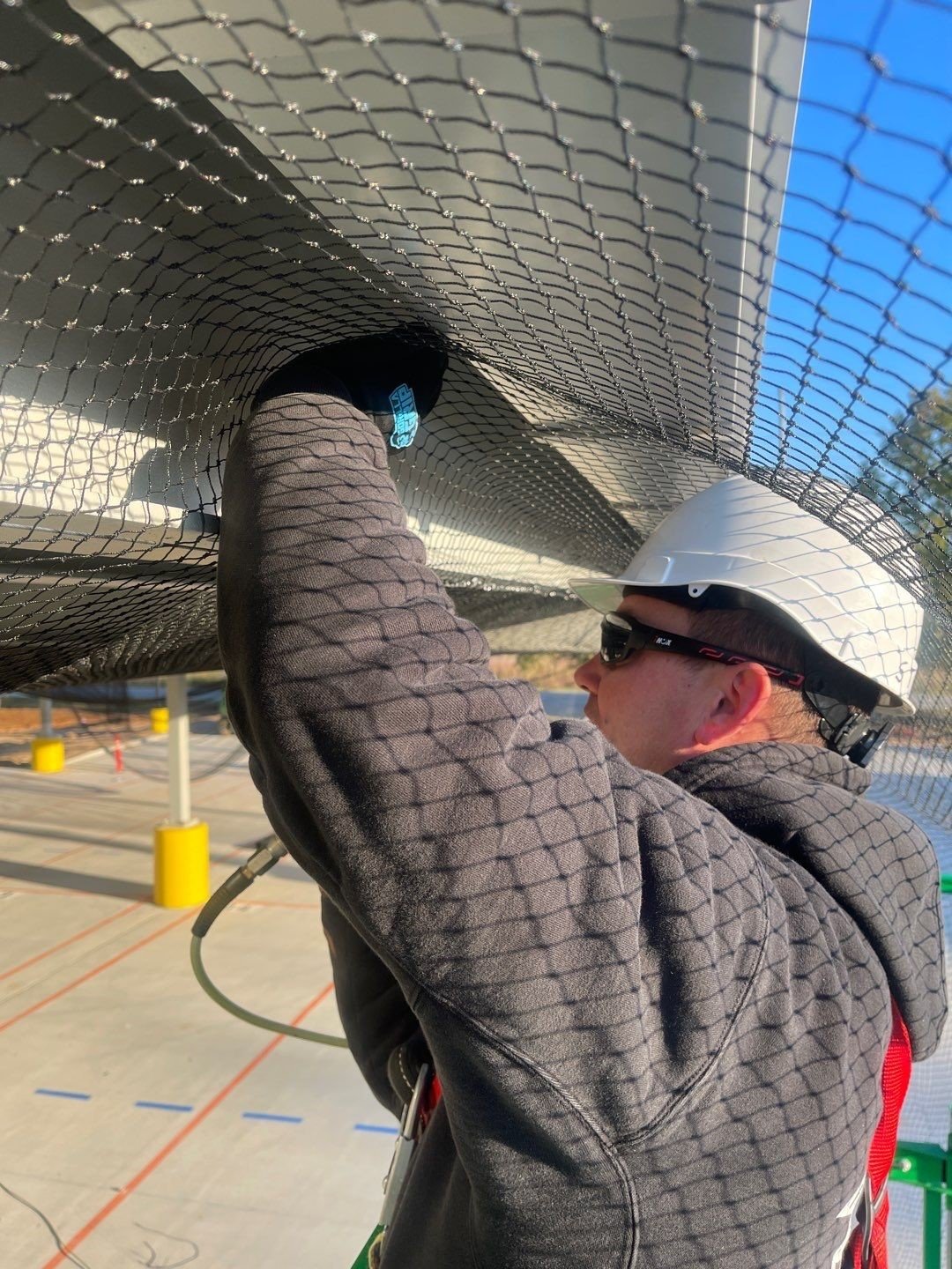 Varment Guard technician installing StealthNet bird exclusion netting on a commercial canopy